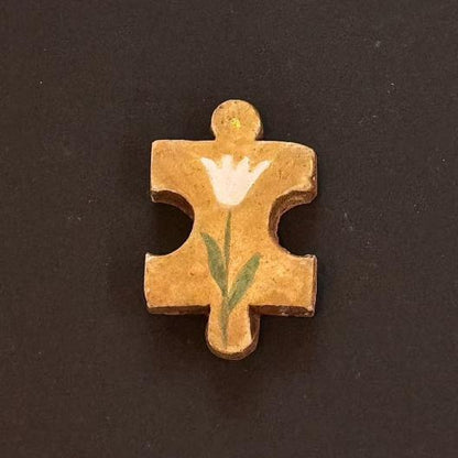Hand-painted clay puzzle magnet with a white tulip-shaped flower on a golden yellow background