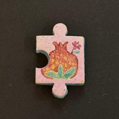Hand-painted clay puzzle magnet featuring a red patterned flower with green leaves on a light pink background