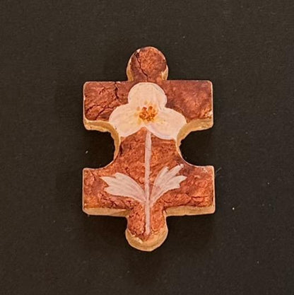 Hand-painted clay puzzle magnet with a pale pink flower and decorative leaves on a reddish-brown background