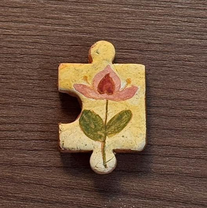 Hand-painted clay puzzle magnet featuring a red flower with green leaves on a pale yellow background