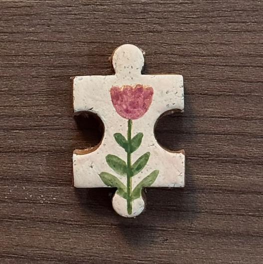 Hand-painted clay puzzle magnet featuring a pink tulip with green leaves on a cream background
