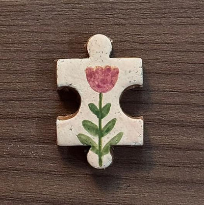 Hand-painted clay puzzle magnet featuring a pink tulip with green leaves on a cream background