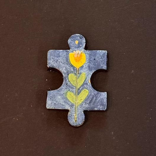 Hand-painted clay puzzle magnet featuring a yellow tulip with green leaves on a blue background