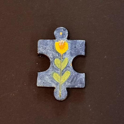 Hand-painted clay puzzle magnet featuring a yellow tulip with green leaves on a blue background
