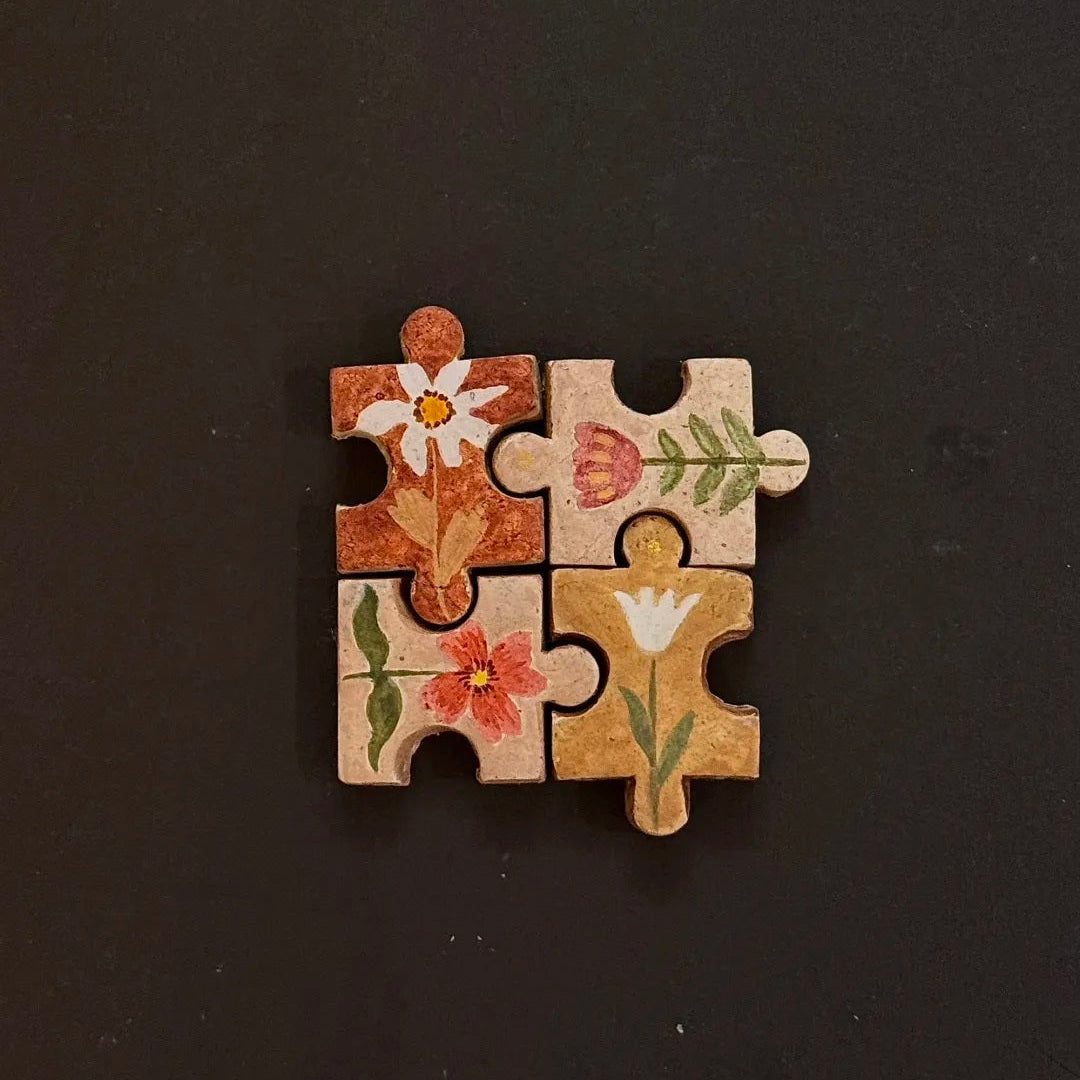 Four hand-painted clay puzzle magnets arranged together with vintage-style botanical illustrations