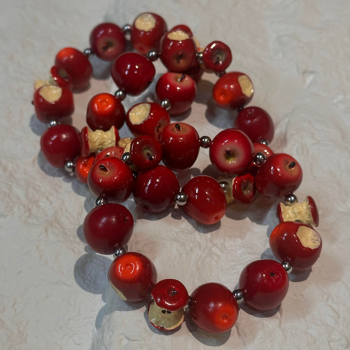 Collection of glossy red apple and bitten apple core beads displayed on a light surface