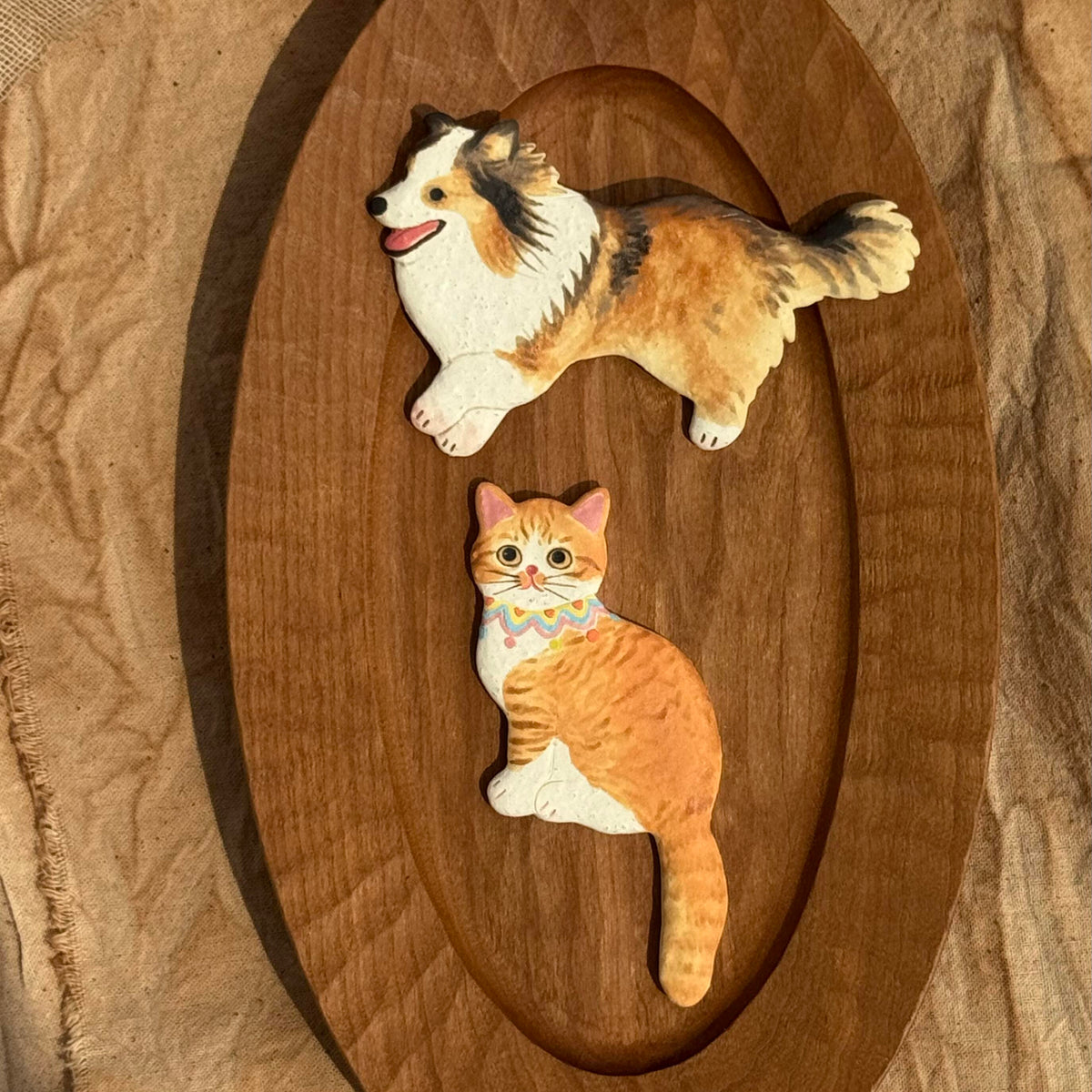 Orange and white ceramic cat magnet displayed on a wooden surface