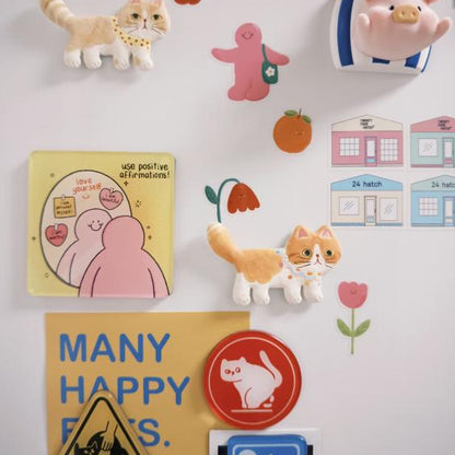 Colorful ceramic cat fridge magnets displayed on a refrigerator with decorative artwork
