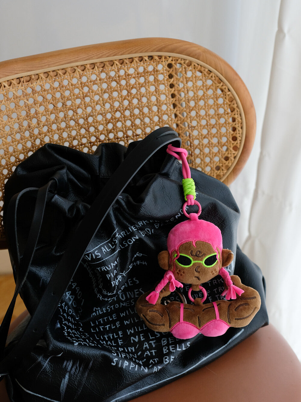 Pink bikini funny muscle girl plush keychain accessorizing a black leather purse