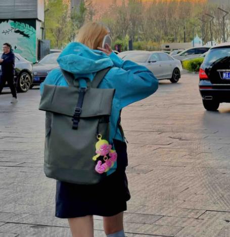 Cute aesthetic plush bag accessory hanging on a backpack in an outdoor street view