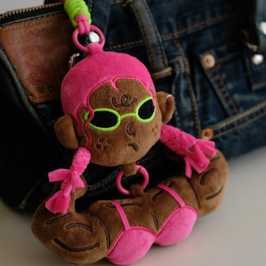 Pink hair funny muscle girl plush keychain styled closely on a dark denim bag