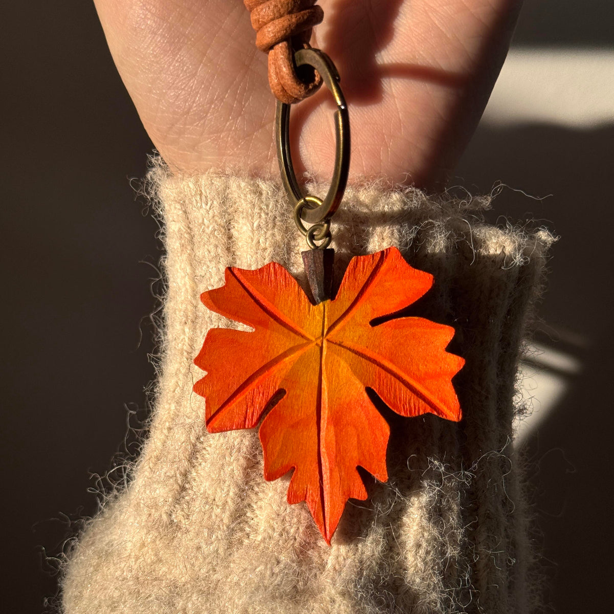 Hand-carved wooden maple leaf charm attached to a woven bag