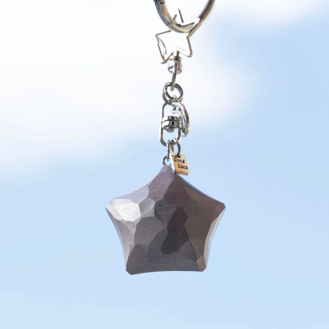Dusty rose wooden star keychain hanging against a blue sky