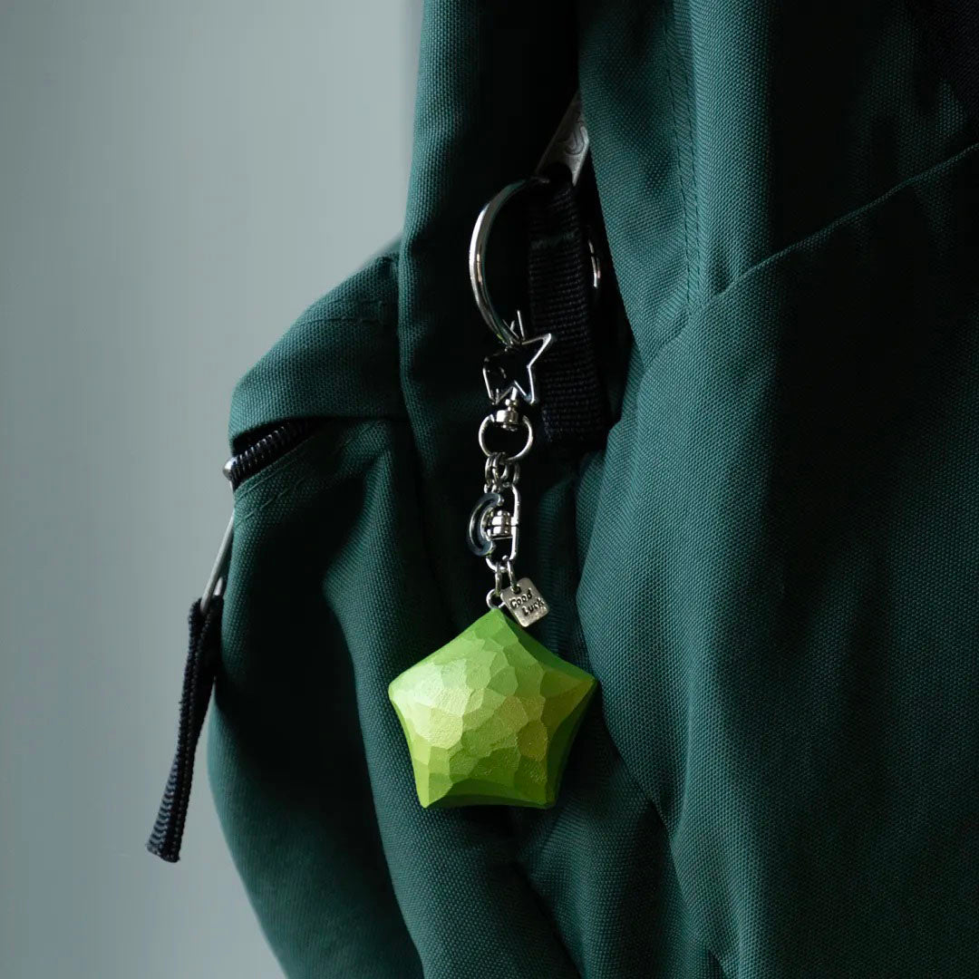 Green wooden star keychain hanging from a green bag