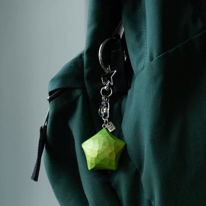 Green wooden star keychain hanging from a green bag