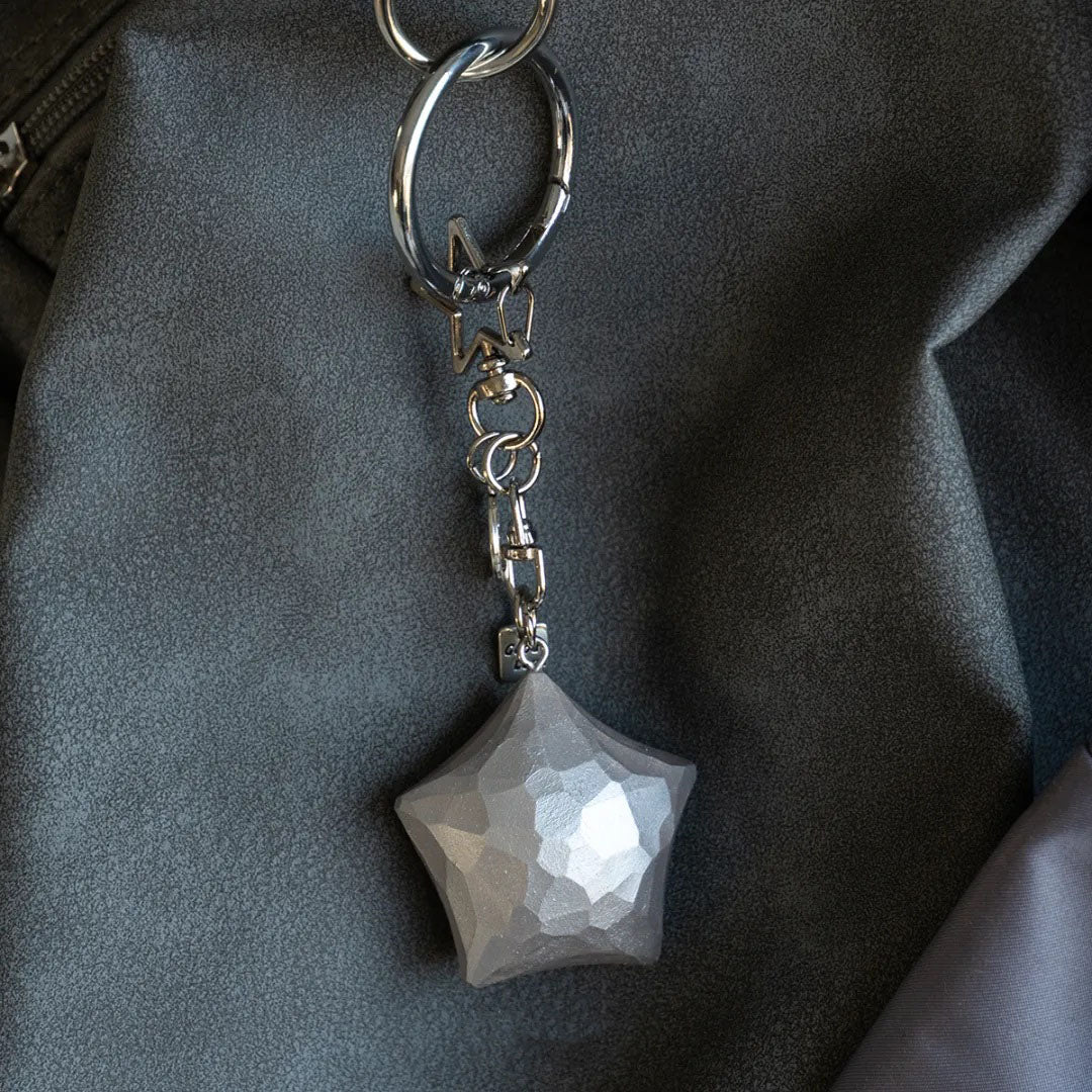 Silver wooden star keychain attached to a dark bag