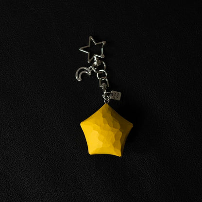 Yellow wooden star keychain with metal moon charm and keyring on a black background