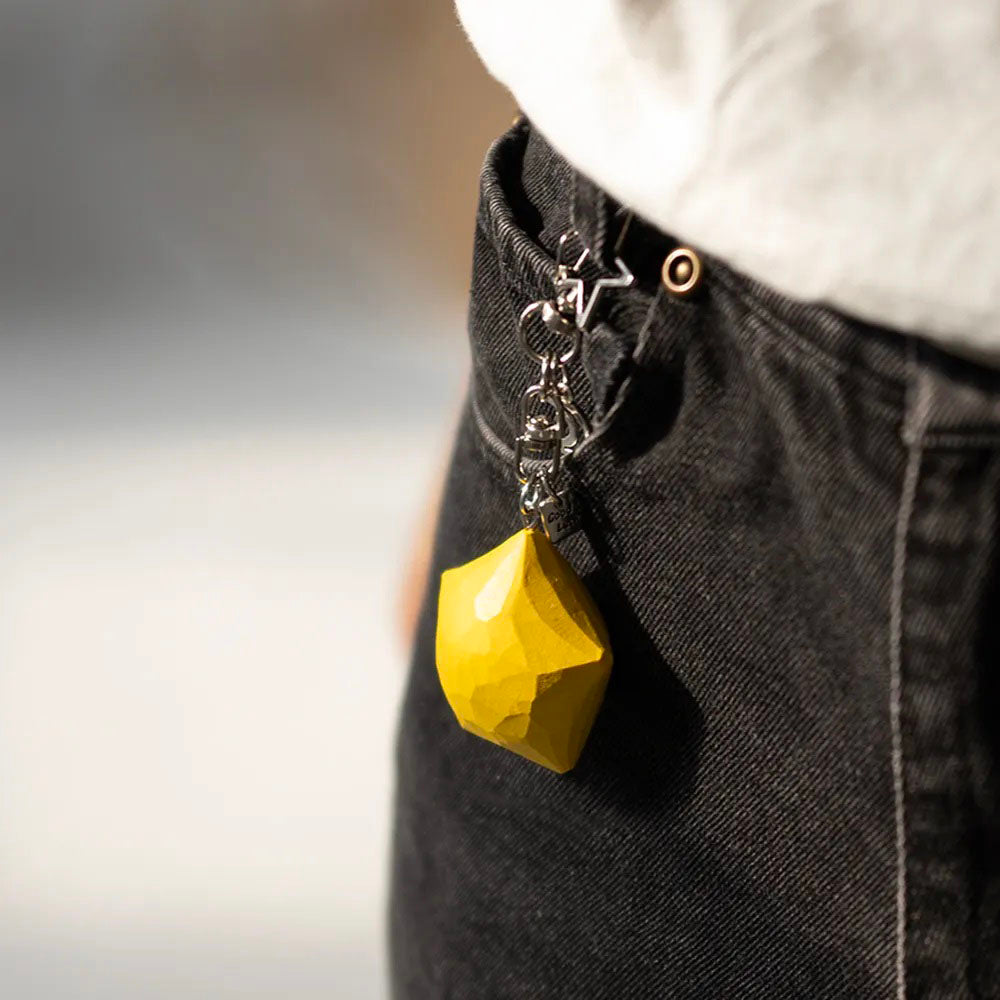 Yellow wooden star keychain attached to a black bag