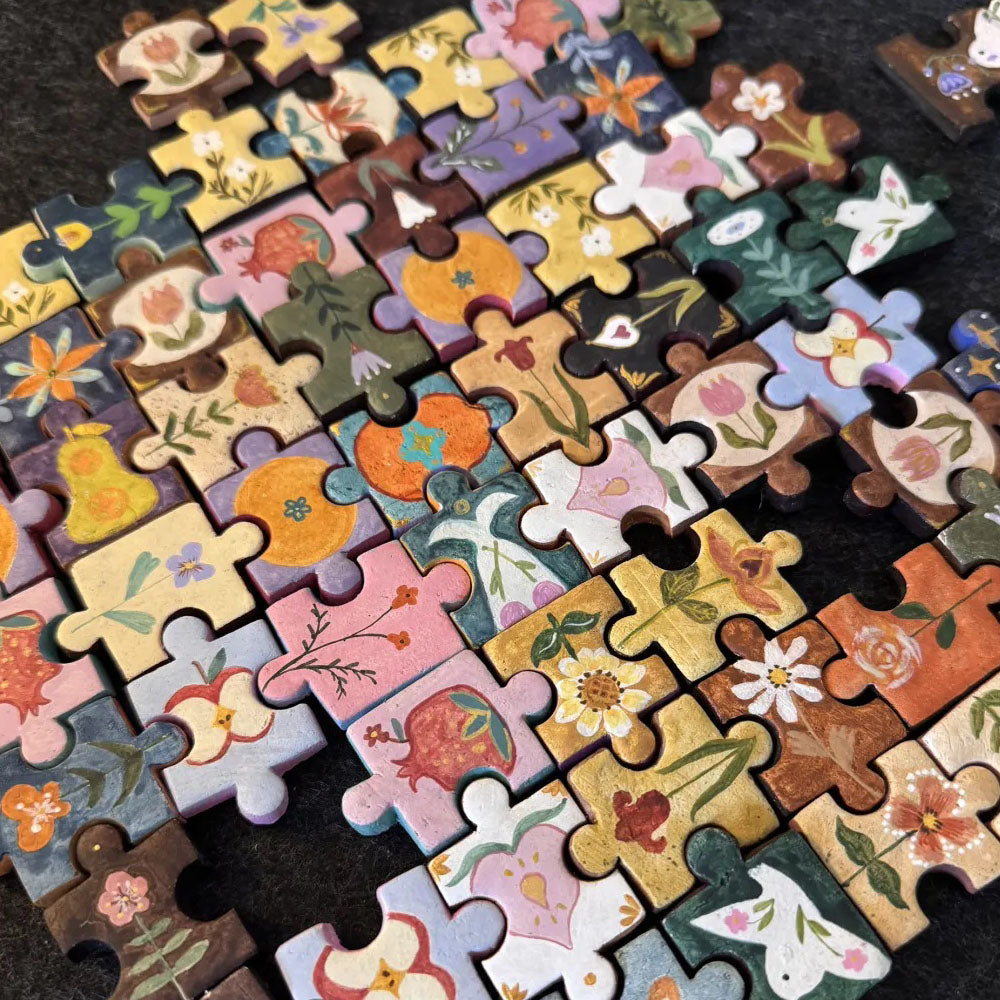 A colorful collection of hand-painted clay puzzle magnets with assorted floral and illustrated designs arranged together