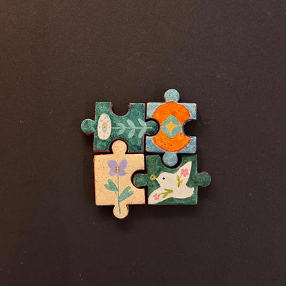 Four hand-painted clay puzzle magnets connected together featuring colorful flowers in warm tones