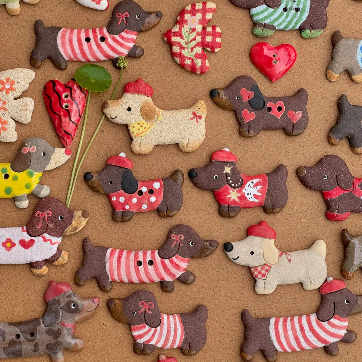 Close-up of handmade ceramic dachshund magnets wearing colorful sweaters, hats, and scarves
