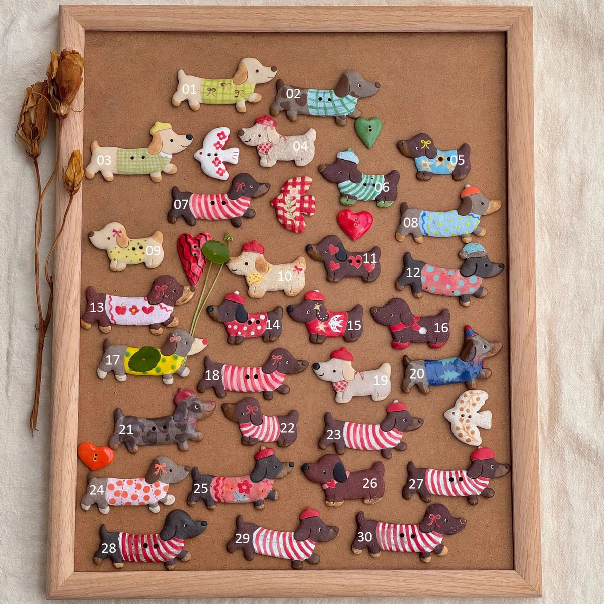 Collection of handmade ceramic dachshund fridge magnets in colorful outfits, displayed with numbered styles on a wooden board