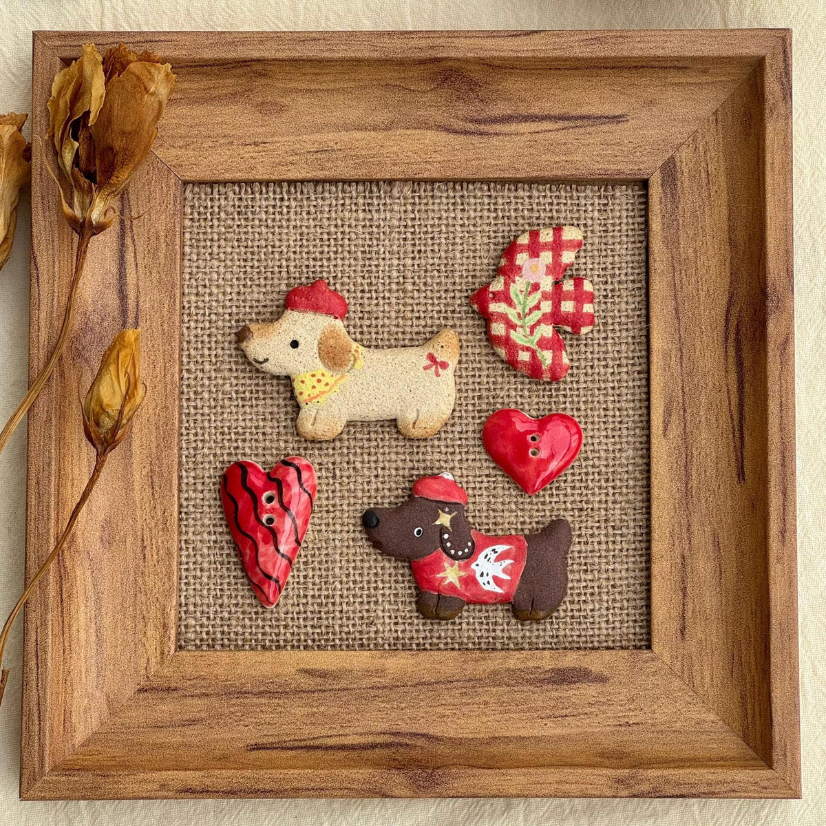 Handmade ceramic dachshund magnets displayed inside a wooden frame with colorful decorative pieces