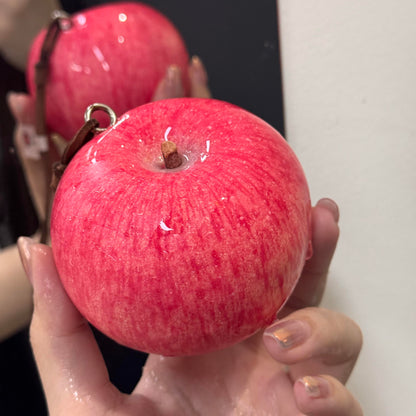Close-up of a lifelike foam apple charm showing its red surface texture and stem.