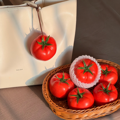 Lifelike tomato bag charm displayed beside a basket of realistic tomato decorations.