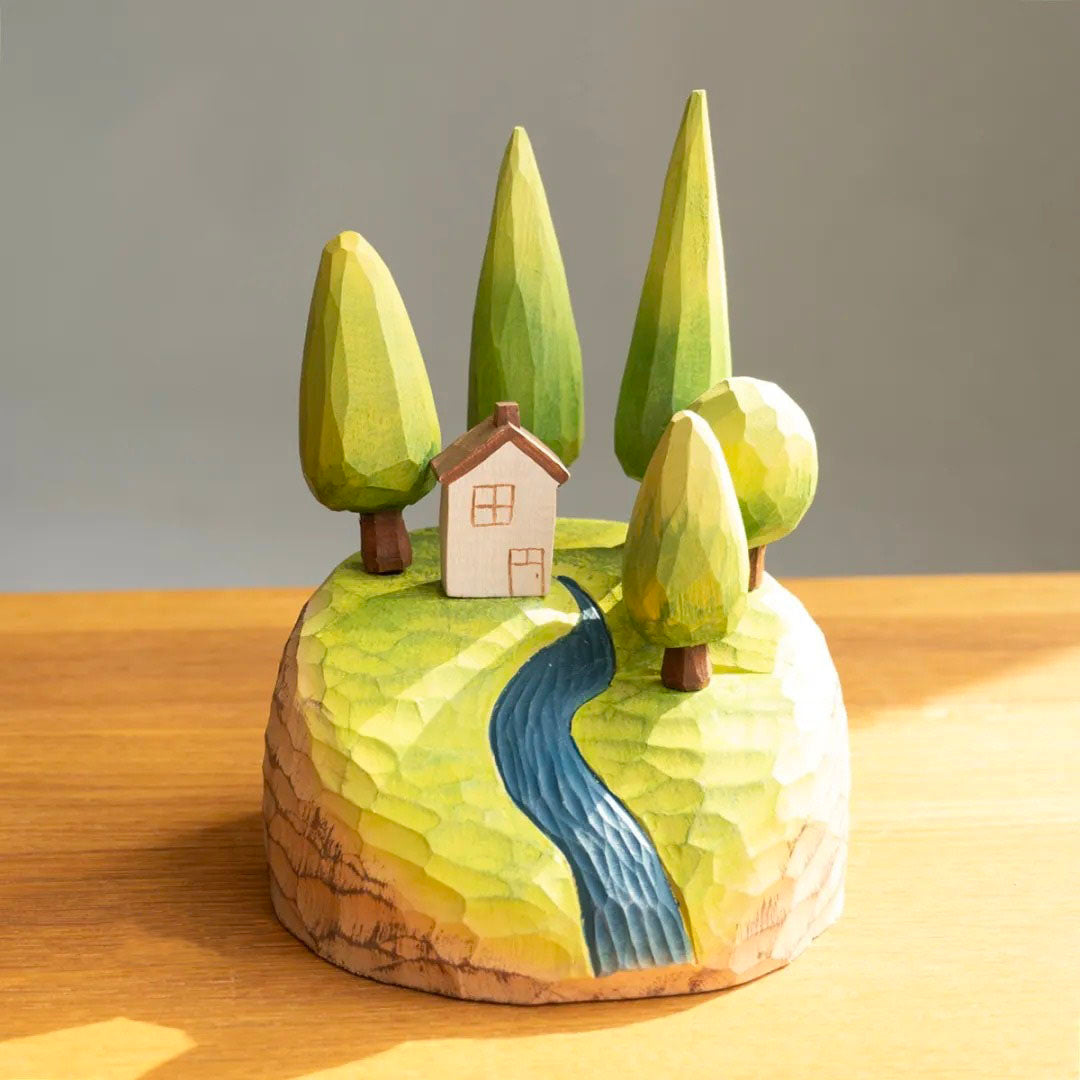 Hand-carved wooden forest landscape with miniature cottage, five green trees, and a winding blue river