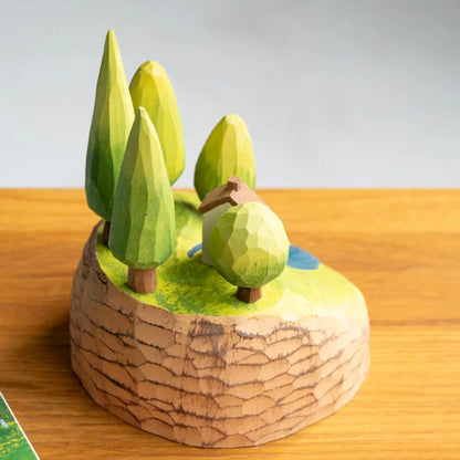 Side view of a miniature wooden forest landscape showing green trees and a small cottage