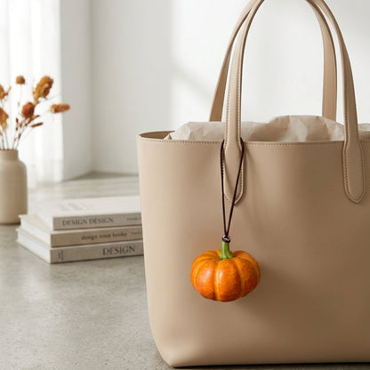 Mini foam pumpkin hanging charm displayed on a beige tote bag.