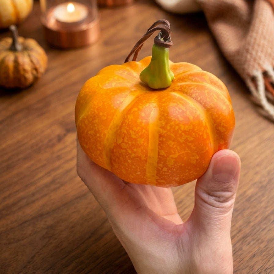 Close-up of a mini foam pumpkin hanging charm showing its orange texture, green stem, and loop.