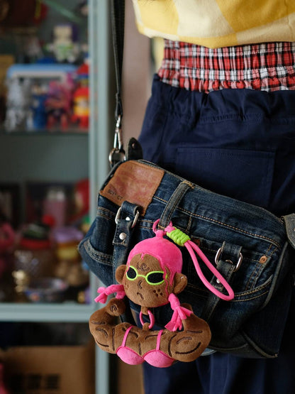 Pink variant of the funny muscle girl plush keychain worn on a crossbody bag