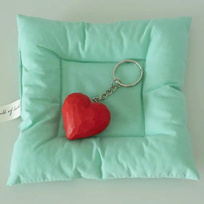 Red wooden heart keychain with metal ring displayed on mint green fabric
