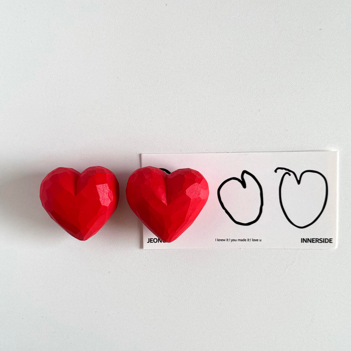 Two red faceted wooden hearts displayed side by side on a light background