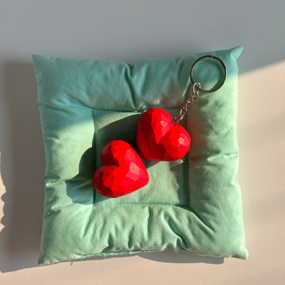 Two red wooden heart keychains displayed together on mint green fabric