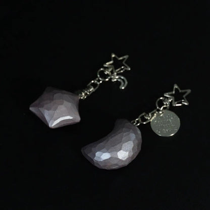 Dusty rose wooden star and crescent moon keychains displayed together on a black background